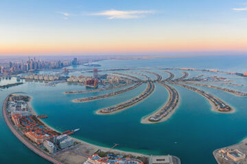 Aerial view of The Palm Jumeirah Island, Dubai Downtown skyline, United Arab Emirates or UAE. Financial district and business area in smart urban city. Skyscraper and high-rise buildings at sunset.