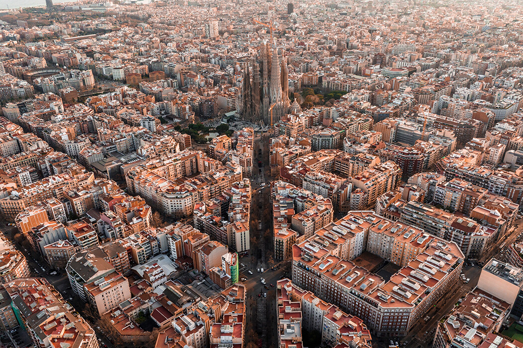 Aerial view of Barcelona City Skyline and Sagrada Familia Cathedral at sunset. Eixample residential famous urban grid. Cityscape with typical urban octagon blocks